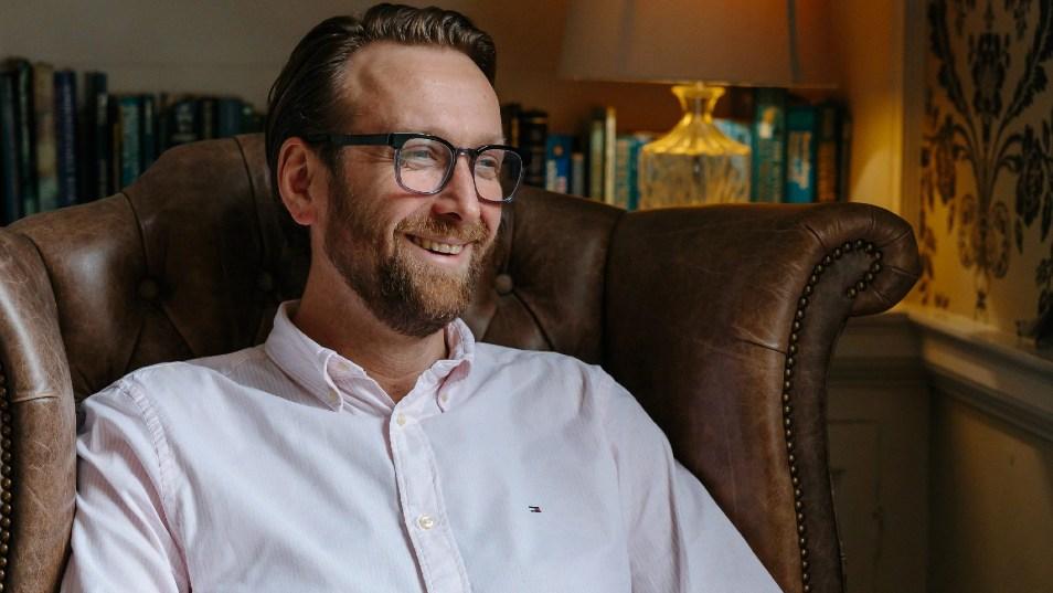 close up of man in light shirt and glasses smiling