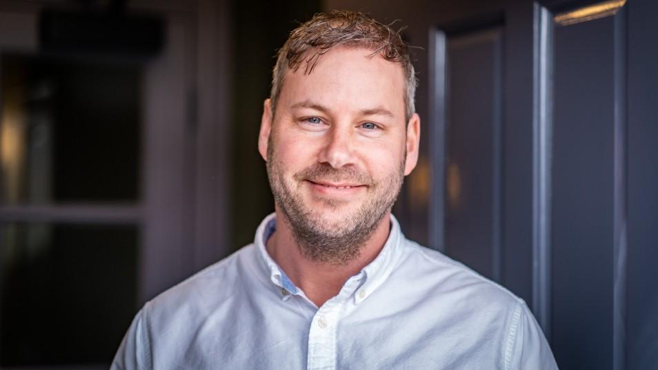 close up head shot of a man smiling in a white shirt